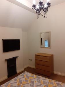 a living room with a television and a dresser at Modern 2nd floor 1 bed apartment in the heart of in Llandudno