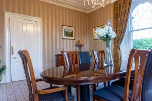 a dining room table with chairs and a vase of flowers at Newton Manor House - Luxury Retreat Sleeps 13 in Fife