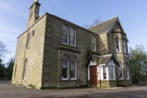an old brick building with a red door at Newton Manor House -7 Bedroom House in Fife
