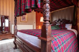 a bedroom with a canopy bed with a red and green blanket at Newton Manor House - Luxury Retreat Sleeps 13 in Fife