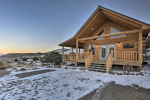 a log cabin in the snow with a front porch at Peaceful Cabin with Panoramic Mtn Views and Hot Tub! in Del Norte