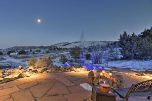a patio with a table and chairs in the snow at Peaceful Cabin with Panoramic Mtn Views and Hot Tub! in Del Norte