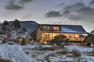 a home in the snow at dusk at Peaceful Cabin with Panoramic Mtn Views and Hot Tub! in Del Norte
