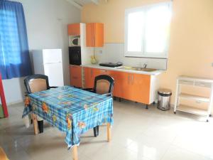 a kitchen with a table and a kitchen with orange cabinets at Maison lumineuse à Bouillante avec vue sur la mer in Bouillante