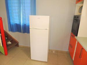 a white refrigerator in the corner of a kitchen at Maison lumineuse à Bouillante avec vue sur la mer in Bouillante