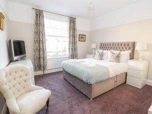 Un dormitorio con una cama y una silla y un televisor. en Livingstone House, en Llandudno