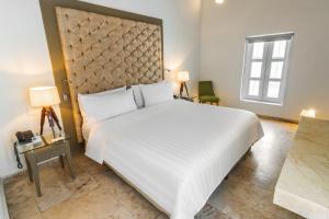 um quarto com uma grande cama branca e uma janela em GHL Collection Armería Real Hotel em Cartagena das Índias