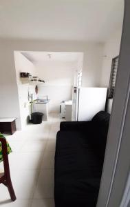 a living room with a black couch and a kitchen at Residencial Alemão in Guarujá