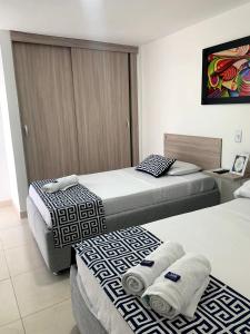 Dos camas en una habitación de hotel con toallas. en Mar de Indias House, en Cartagena de Indias
