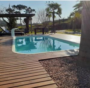 a swimming pool on a wooden deck with a table at Cappio Pousada e Lazer in Bento Gonçalves