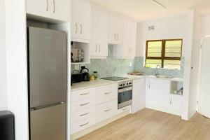 a kitchen with white cabinets and a stainless steel refrigerator at Umdloti Cabanas in Umdloti