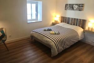 1 dormitorio con 1 cama con manta a rayas en blanco y negro en Pierre et mer au cœur de Saint Cado, en Belz