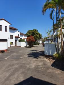 a parking lot with a palm tree and a building at Hacienda Holiday Home in Richards Bay