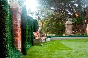 eine Bank, die im Gras im Garten sitzt in der Unterkunft Hostal Jardin Secreto in Santander
