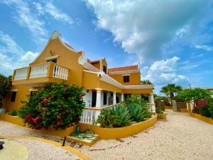 a yellow house with a balcony and flowers at Landhuis Belnem Bonaire in Kralendijk