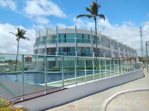 un edificio con piscina y palmeras en Apto Areias beira-mar en Barra de São Miguel