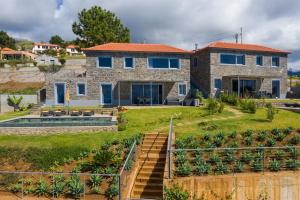 a stone house with blue windows and a yard at Villa Flora - Nature & Tranquility - Heated pool optional in Jardim do Mar