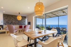 a dining room with a table and chairs with a view of the ocean at Villa Flora Calheta Sunset & Ocean Views in Jardim do Mar +35 photos
