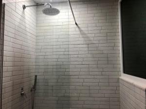 uma casa de banho com um chuveiro e uma parede de tijolos brancos. em Nikki Apartments 3 em Tirana