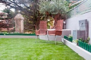 drie stoelen en een tafel in een tuin met gras bij Hostal Jardin Secreto in Santander