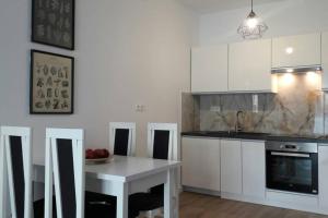 una cocina con armarios blancos y una mesa con fruta. en Lux Apartment close to Medicover and Paley, en Varsovia