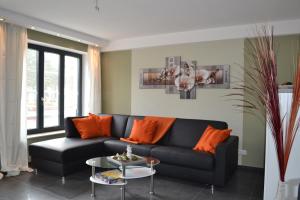 a living room with a black couch and orange pillows at Apartment mit Meeresblick in Binz