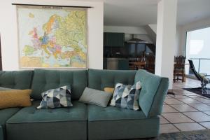 un sofá verde con almohadas en la sala de estar. en Somnar Panoramaloft mit Hästens Betten - Rheinblick 150qm en Neuss