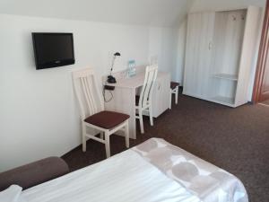 a room with a bed, chair, desk and television at Hotel Jester in Wrocław