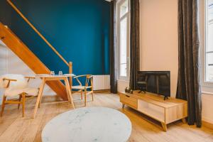 a living room with a blue wall and a table and a tv at Hyper centre - Hôtel de Ville in Reims