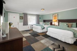 a hotel room with two beds and a television at Ocean Inn on Nantasket Beach in Hull +27 photos