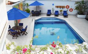 una piscina con sillas, mesa y sombrilla en Apartamentos Commodore Bay Club, en San Andrés