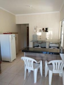 uma cozinha com um frigorífico branco e 2 cadeiras brancas em Chalés São Mateus em Ubatuba