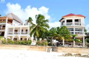 a white building on the beach with palm trees at Villa Mina beachhouse in Jambiani