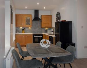 a kitchen with a table and chairs and a black refrigerator at Machermore Castle East Lodge in Newton Stewart