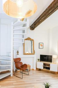 uma sala de estar com uma cadeira e uma televisão em Les Cerisiers - Duplex de Standing au Centre de Namur em Namur