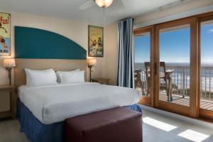 1 dormitorio con 1 cama y balcón con vistas. en Seaside Inn - Isle of Palms en Isle of Palms