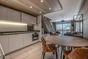 una cucina e una sala da pranzo con tavolo e sedie di Le lodge des Cîmes, Méribel Centre, Magnifique duplex cosy a Méribel