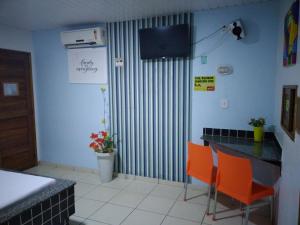 eine Küche mit orangefarbenen Stühlen und einem Tisch mit einem TV in der Unterkunft Pousada Tropical (Adults Only) in Marituba