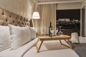 um quarto com uma cama e uma mesa com copos de vinho em A.P. Acropolis View Apartments em Atenas