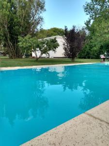 una piscina azul con una casa en el fondo en AntoJos en Ramallo