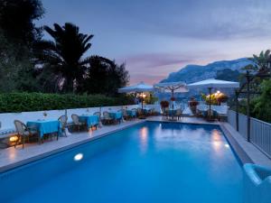 einen Pool mit Tischen, Stühlen und Sonnenschirmen in der Unterkunft Hotel Villa Brunella in Capri