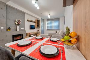une salle à manger avec une table, des assiettes et des verres à vin dans l'établissement Apartman Aroma Lux 25, à Zlatibor