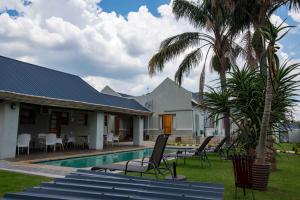 a house with a swimming pool and palm trees at Presidents Boutique Lodge by Ilawu in Vryheid