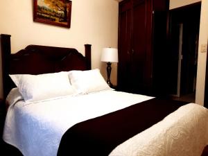 una camera da letto con un grande letto con lenzuola e cuscini bianchi di Hotel Boutique La Albertina a San Martín Texmelucan de Labastida