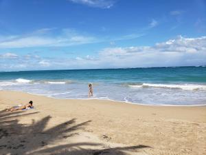 two people playing in the water on a beach at Andalucia Guest House in San Juan