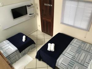 1 dormitorio con cama, TV y calcetines blancos en Pousada Recanto Maguary, en Alter do Chao