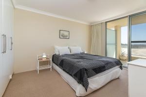 a bedroom with a bed with a view of the ocean at Beachpoint, Unit 402, 28 North Street in Forster