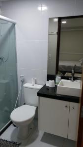 La salle de bains est pourvue de toilettes, d'un lavabo et d'un miroir. dans l'établissement Apartamento 4 suítes, 10 pessoas, 100 m da praia, próximo ao centro, à Porto de Galinhas