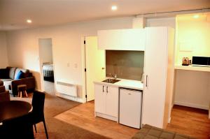uma cozinha com armários brancos e uma sala de estar em St James Apartments em Queenstown