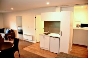 a kitchen with white cabinets and a living room at St James Apartments in Queenstown